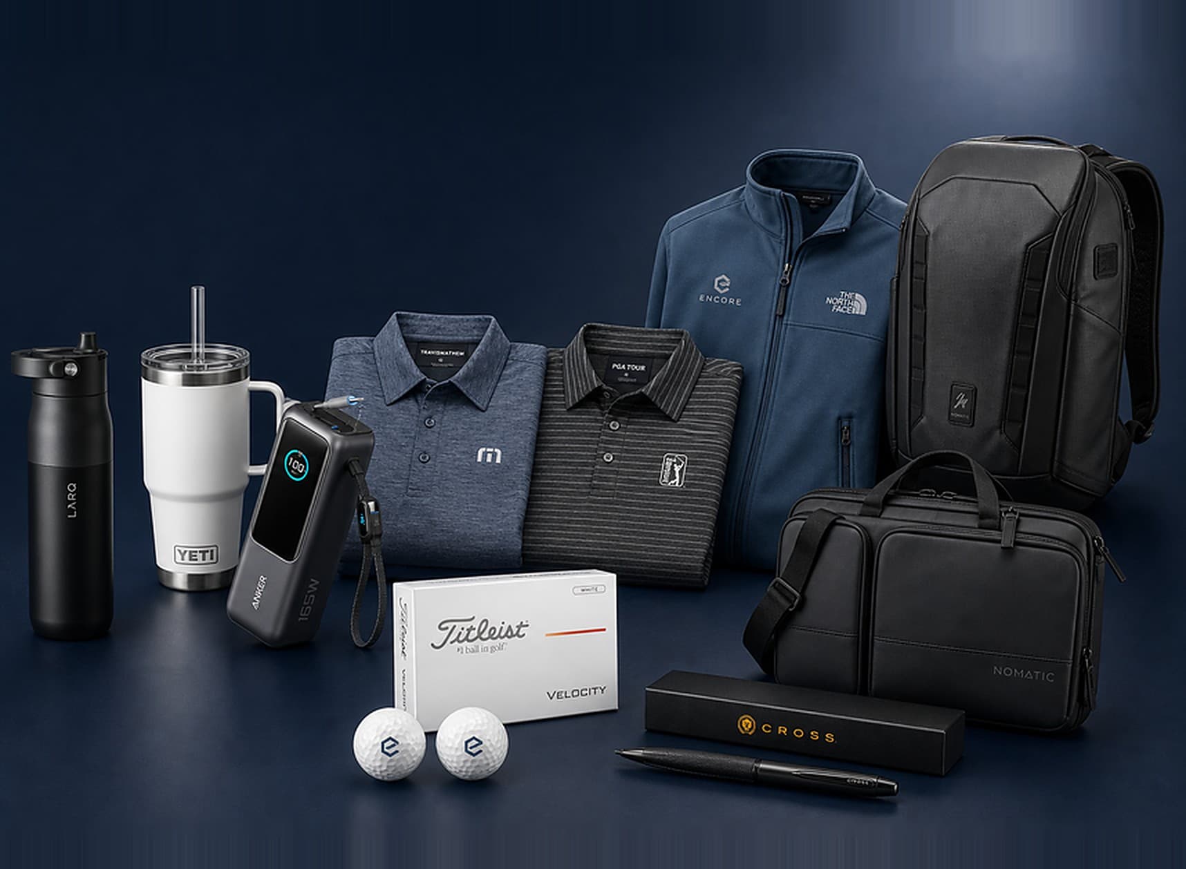 Branded corporate gift lineup: LARQ and YETI drinkware, an Anker power bank, TravisMathew and PGA Tour polos, an Encore-logo The North Face jacket, Nomatic bag and backpack, Titleist golf balls, and a Cross pen